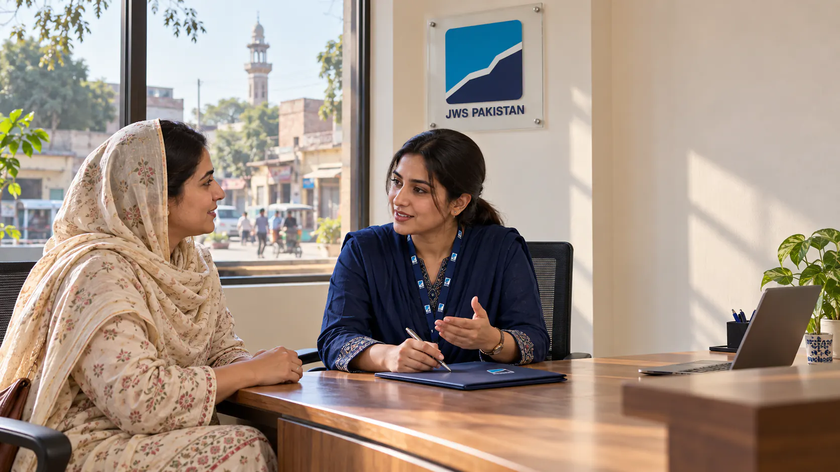 A woman speaking with a JWS Pakistan adviser in a welcoming branch office